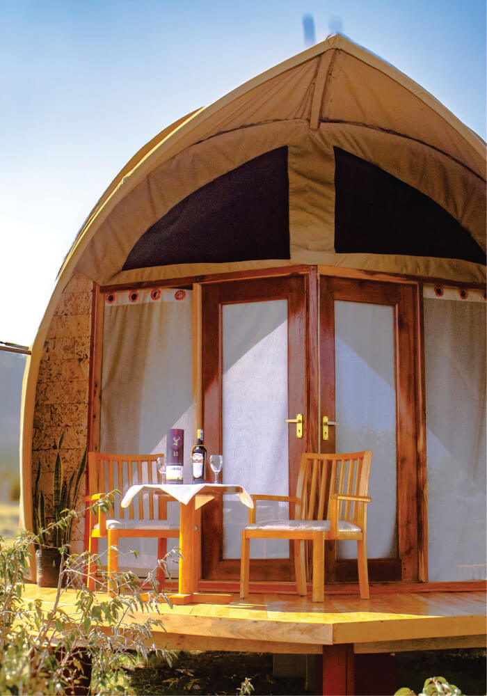 Wooden glamping pod with a small table and chairs on a wooden deck.